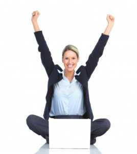 Woman cheering and sitting on the floor with a laptop in her lap